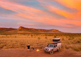 a man setting up a bonfire outside his 4WD in El Questro