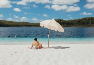 A woman relaxes on the white sand at Lake McKenzie(Image: Tourism and Events Queensland)