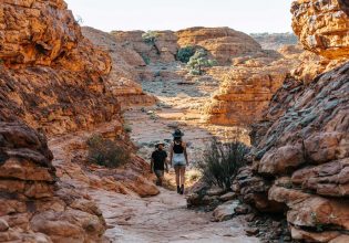 Man and woman trekking across Kings Canyon. (Image: Tourism NT and Jess Caldwell & Luke Riddle)