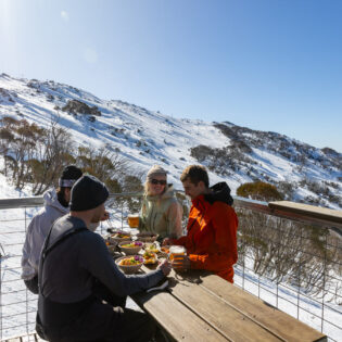 friends dining on the outdoor deck of Black Sallees, Thredbo
