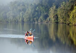 a mother and daughter kayaking through the waters of Pieman River