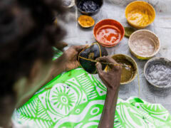 a close-up of a Tiwi artist painting