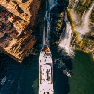 People gather on the deck under King George Falls in the Kimberley on a True North cruiise