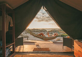 Guest sips a drink in a hammock at Sal Salis as the sun sets
