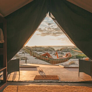Guest sips a drink in a hammock at Sal Salis as the sun sets