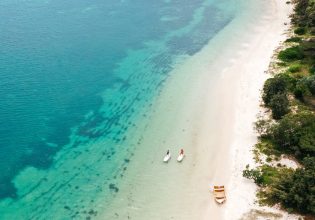 Aerial shot of two paddleboarders next to wooden row boat.