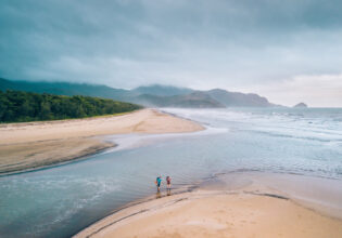 Two people crossing a beach along the Thorsborne Trail